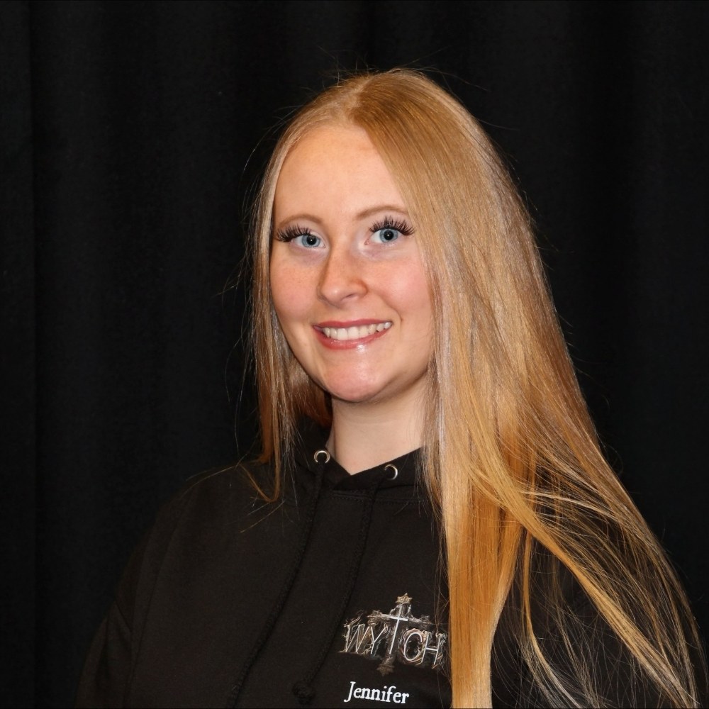 student with long blond hair staring straight at camera wearing black jumper 