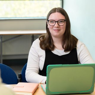 Jess Fensom on her laptop, smiling at her colleague