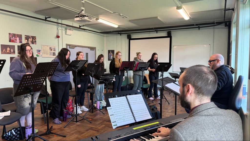 photo of the cast of this is the moment show - seven of the students standing rehearsing
