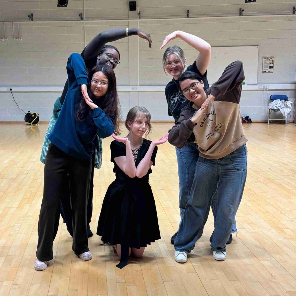Students in studio creating a heart shape with their arms together