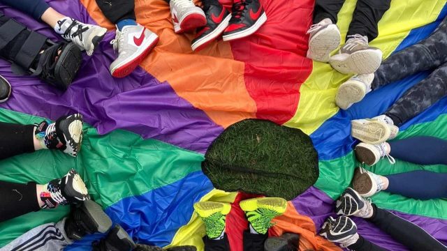 photo of childrens feet laying on the floor underneath a rainbow blanket.