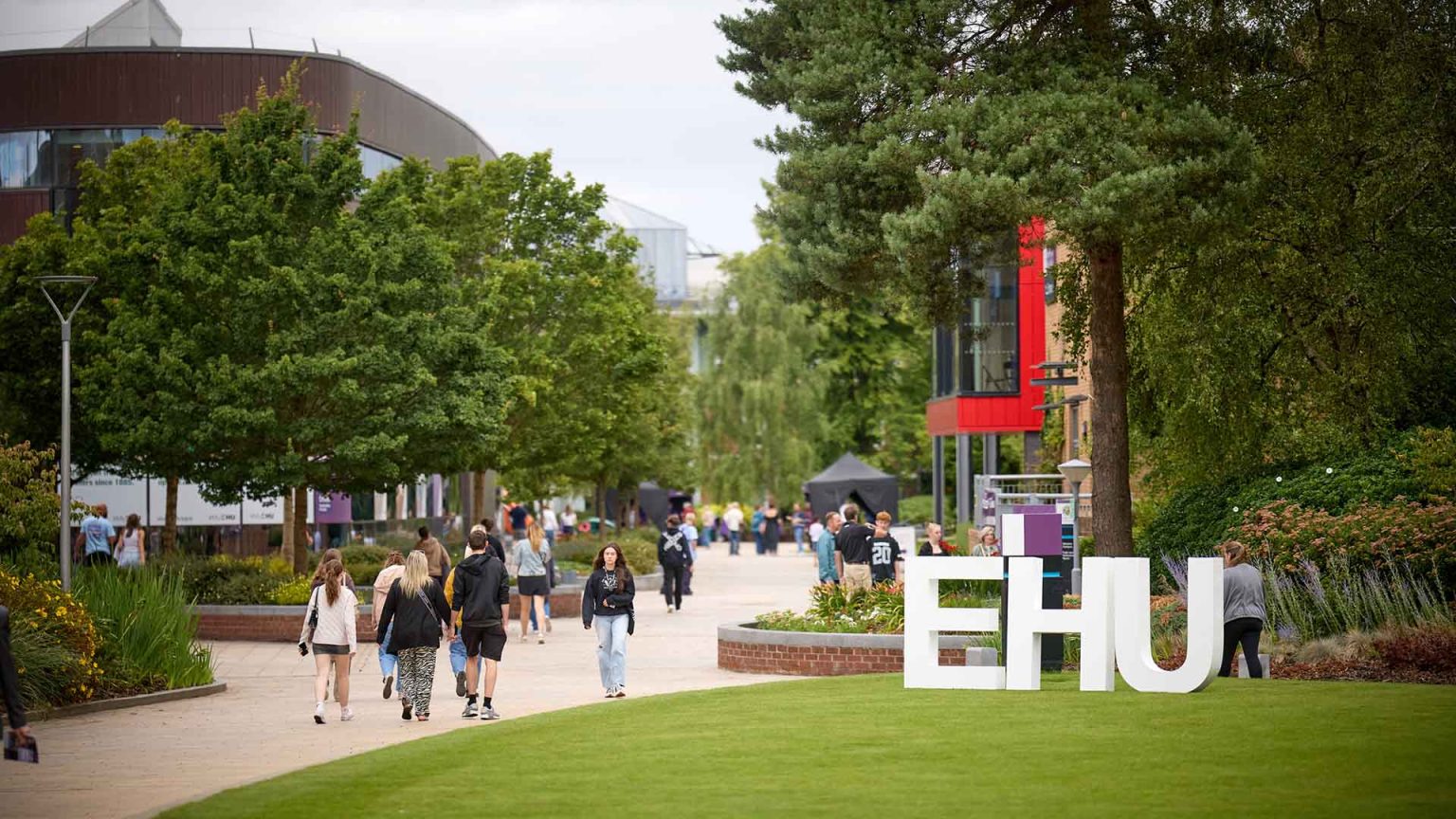 A shot of campus by the Hub with large "EHU" letters on the grass in front of the Wilson Building.