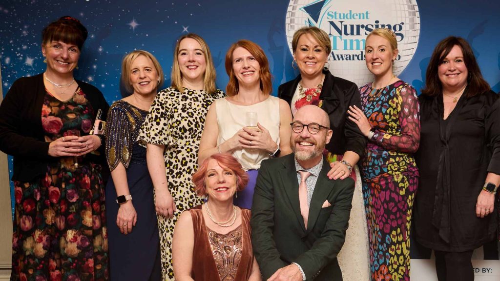 nine Edge Hill staff standing behind Student Nursing times banner