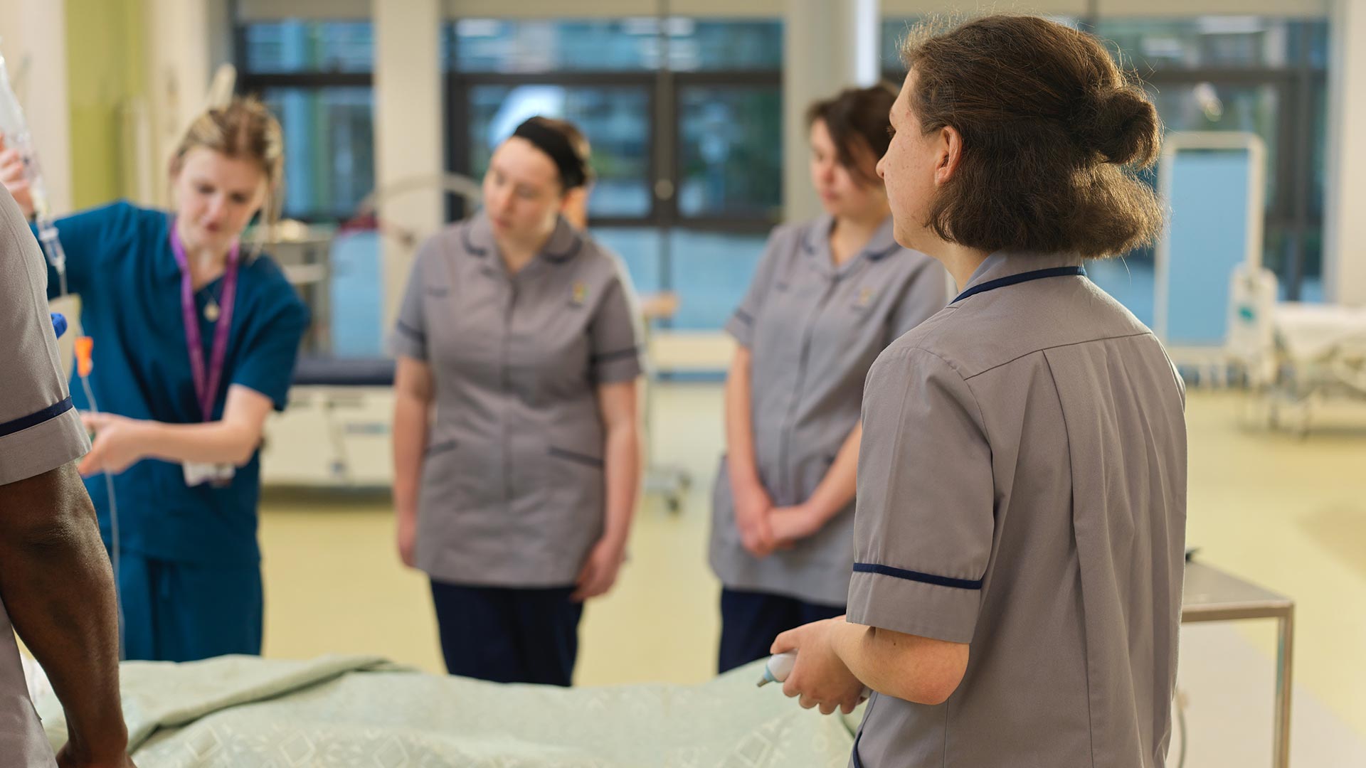 4 nursing students watching their tutor demonstrators how to use the medical equipment