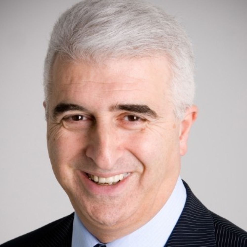 Max looking into camera smiling, wearing blue shirt, black suit.