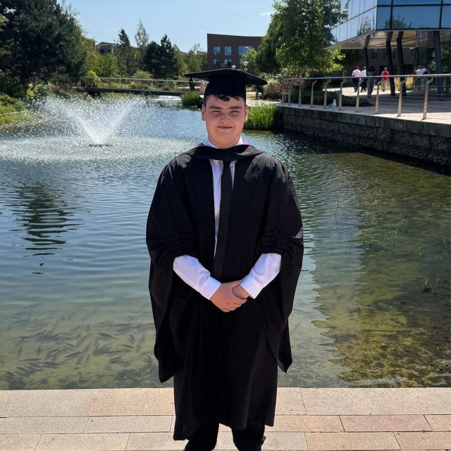 Callum Poskitt in a cap and gown at their graduation.