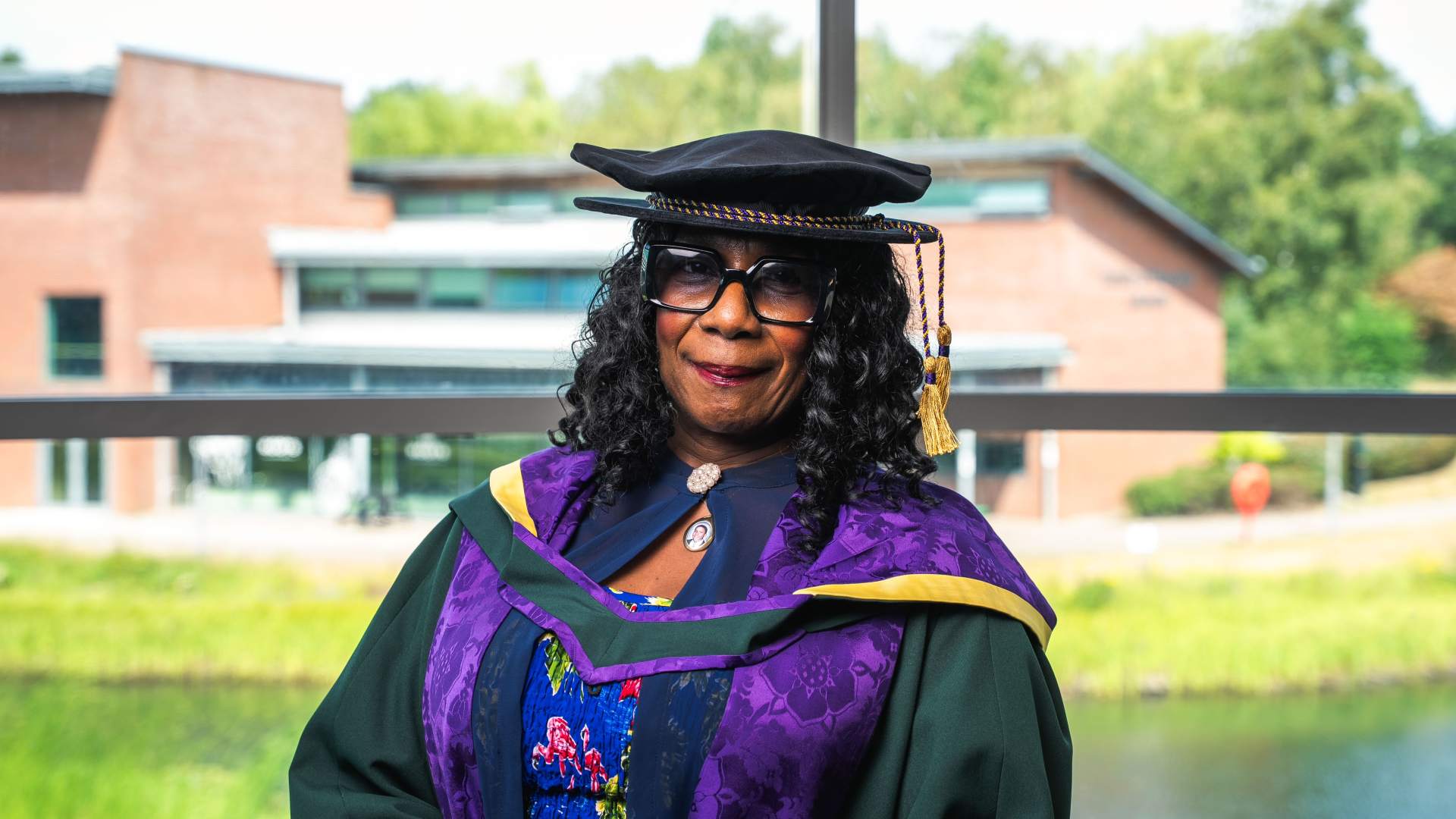 Gee walker wearing lasses with gown looking at camera