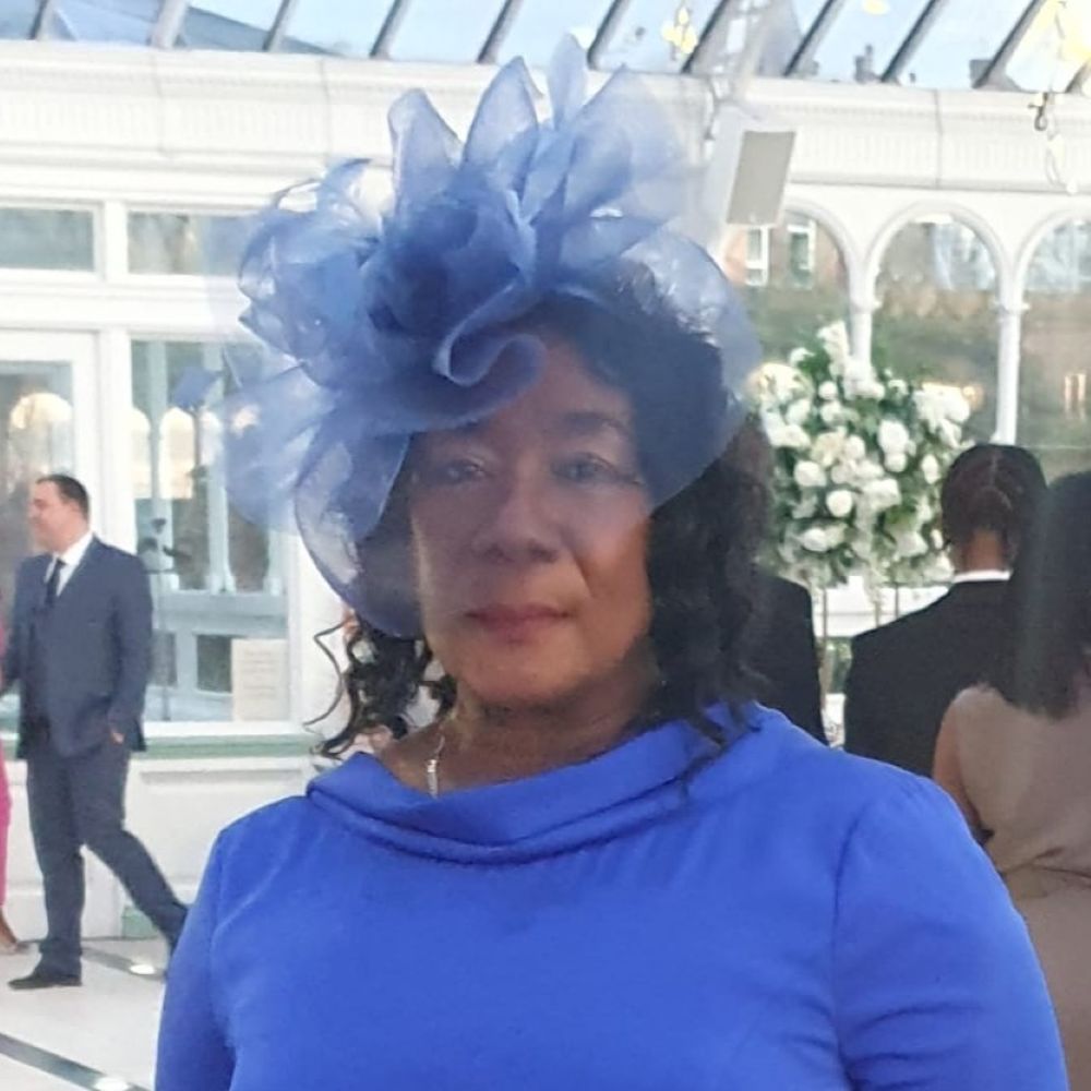 Gee Walker wears a blue dress and blue fascinator.
