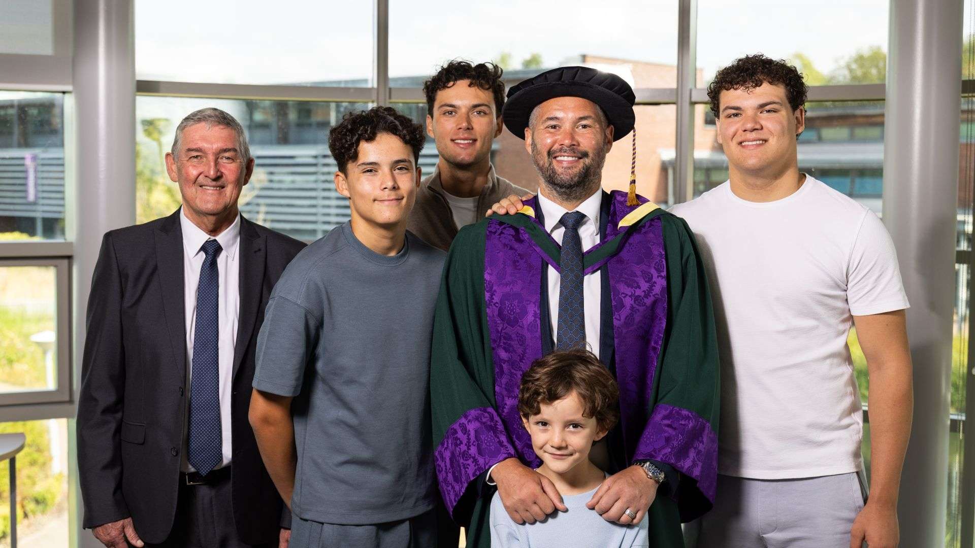 Tony Bellew wearing his graduation gown standing with his family