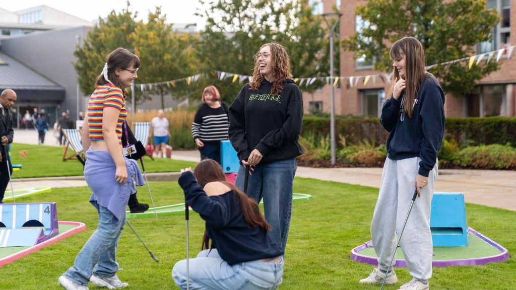 Students enjoying playing crazy golf on the lawn in front of the Catalyst building during Welcome Week