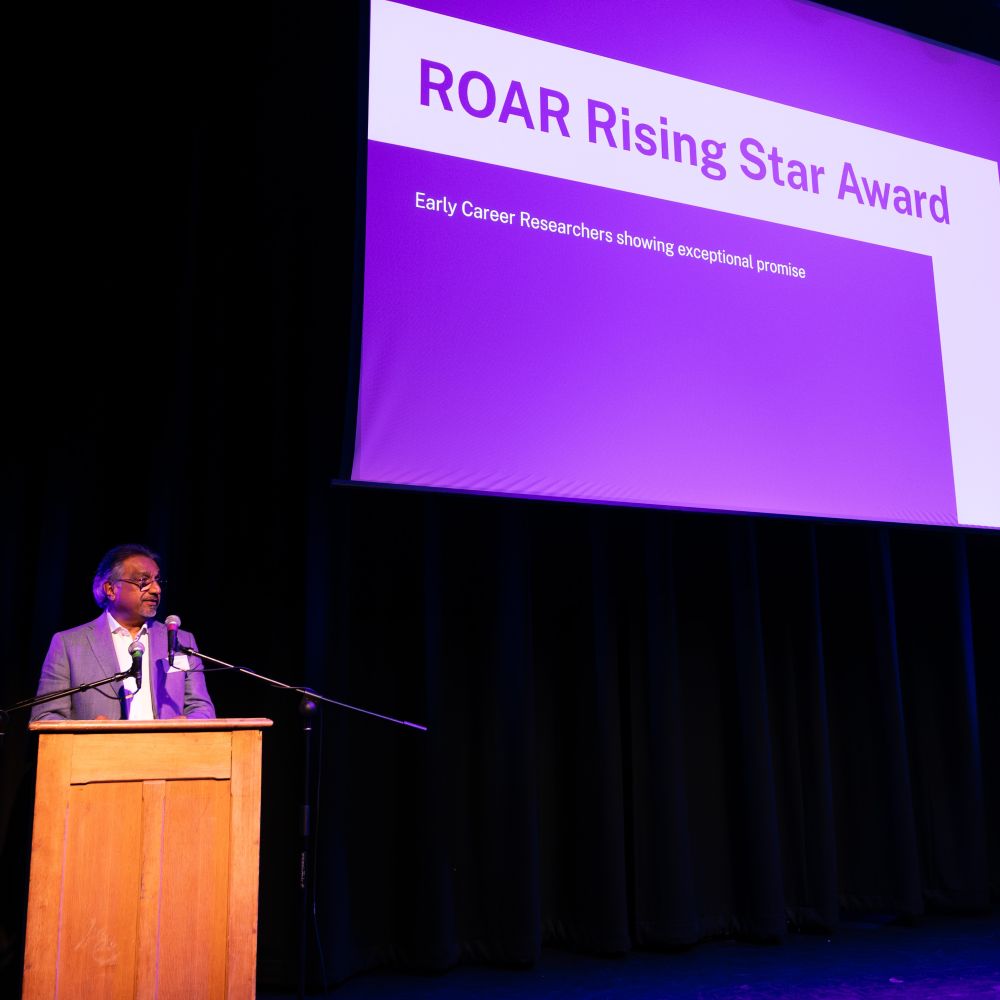 Roar awards with man standing on podium with presentation behind him