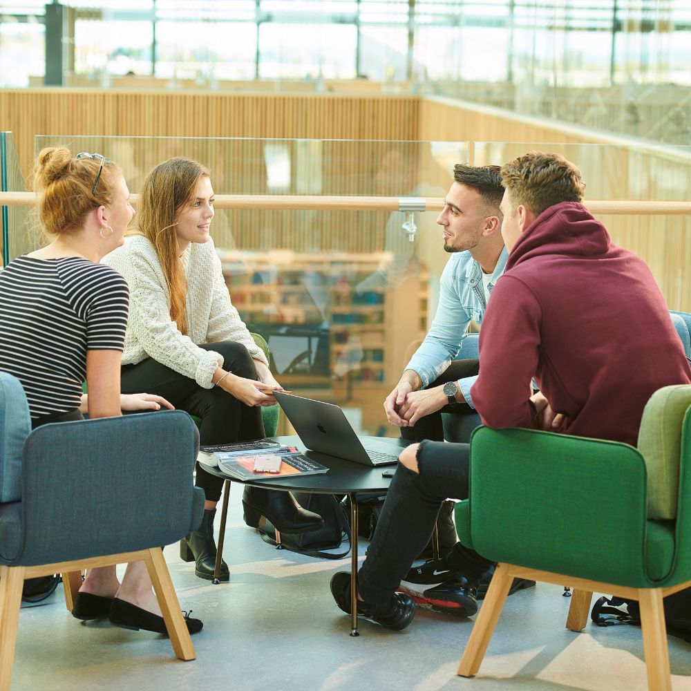 four people sitting around a small table talking to each other.