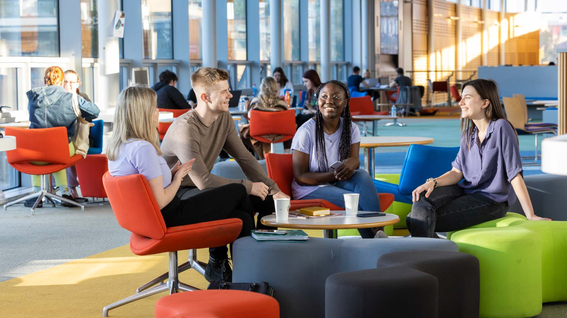 Four students sat round a table having a chat in the hub
