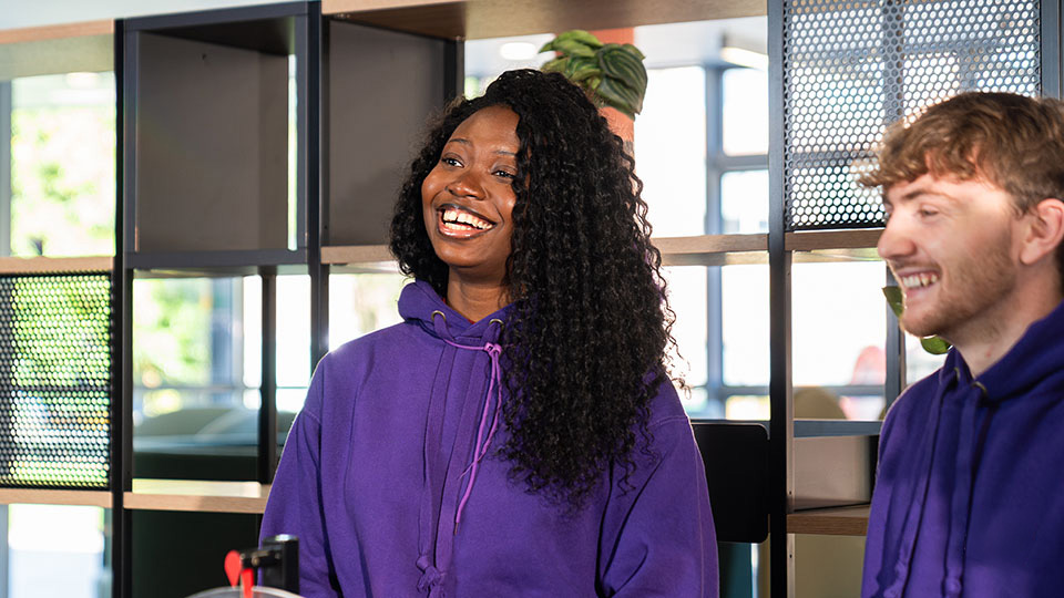 female campus connector in purple jumper at the student life arch