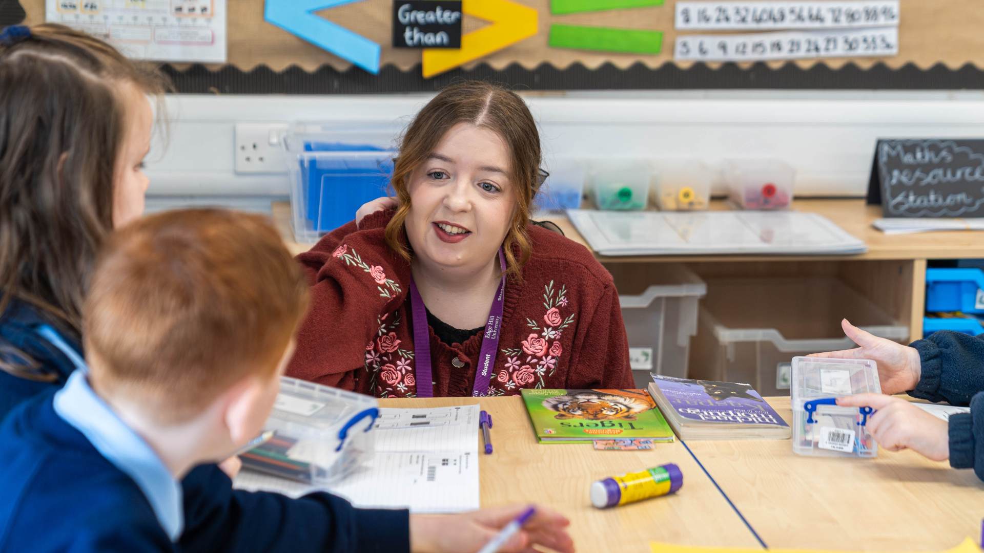 Edge Hill student speaking to primary school students a sthey work on a table