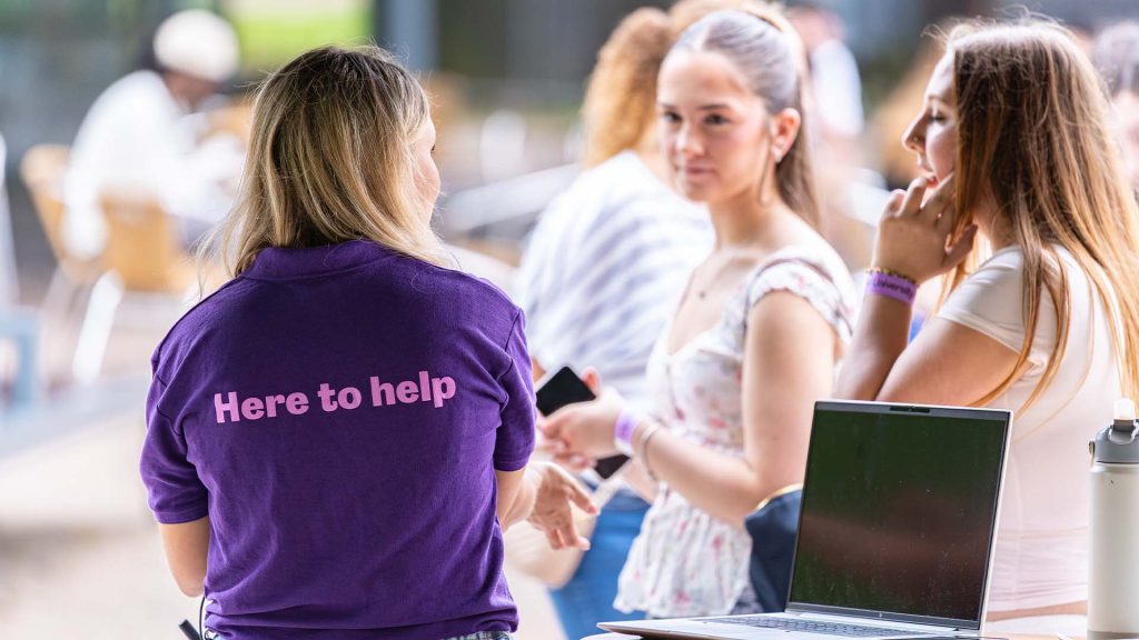 A member of staff helping visitors at an on campus event