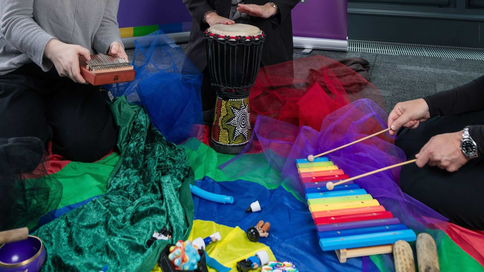 a floor full of fabric, instruments and someone playing african drum