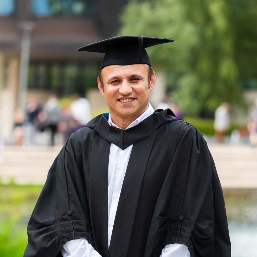 Profile image of Haroon standing outside Edge Hill pound, smiling at camera wearing cap and gown.