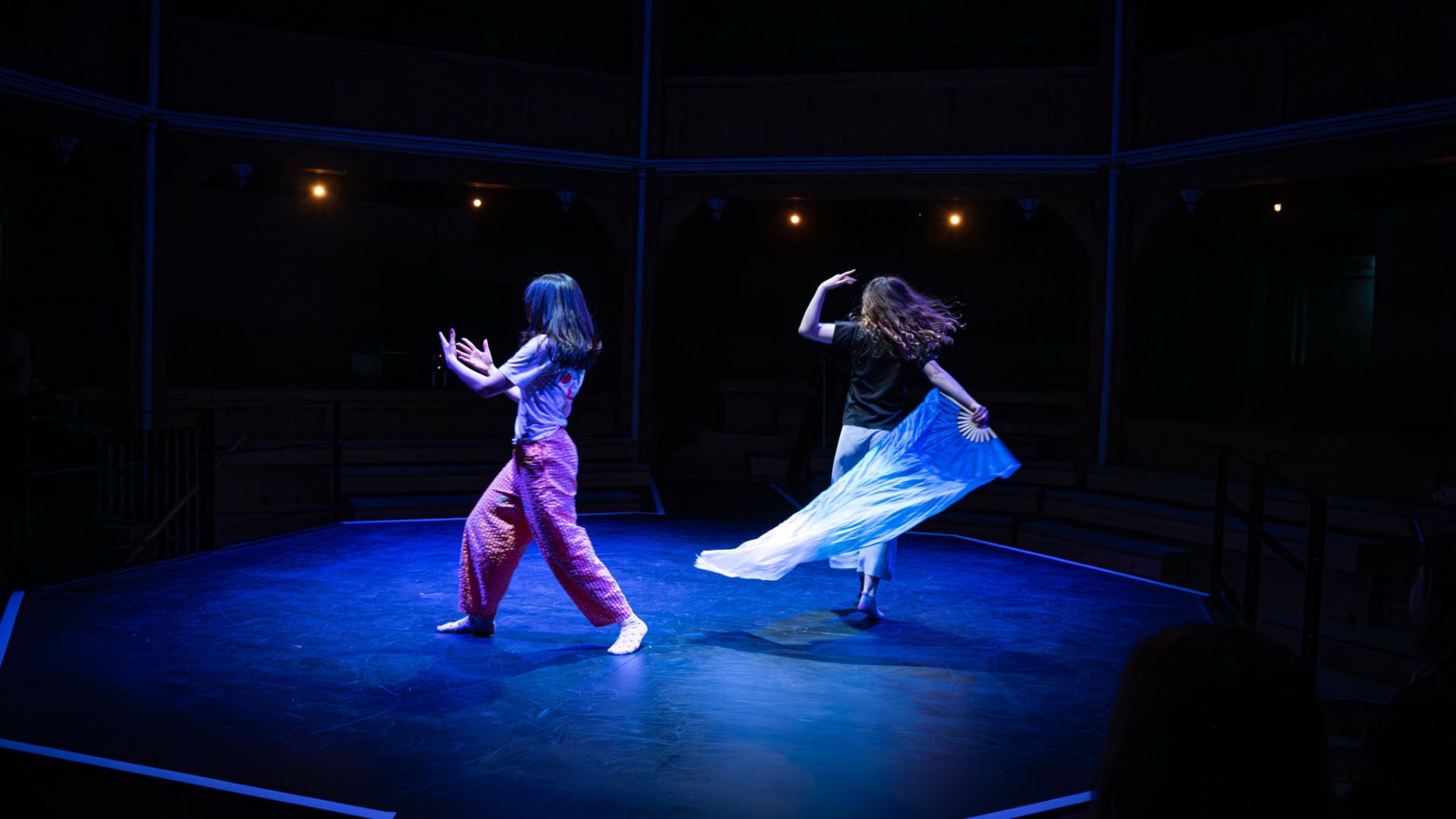 two young women on a theatre stage dancing.