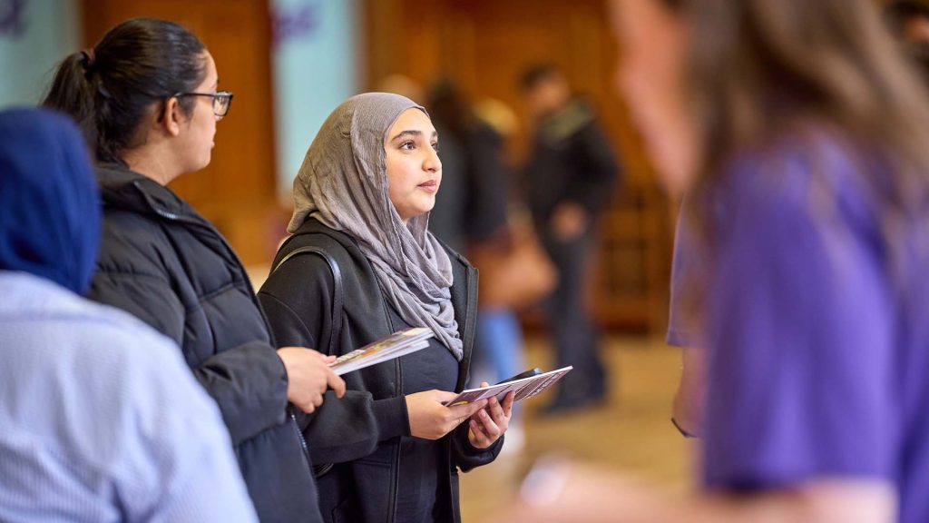 Prospective students attending an on campus event receive information from a member of staff.