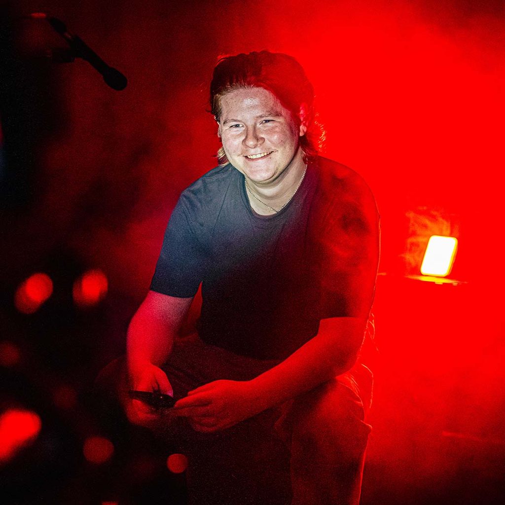 Nathan takes a rest on set, with a red-lit background.