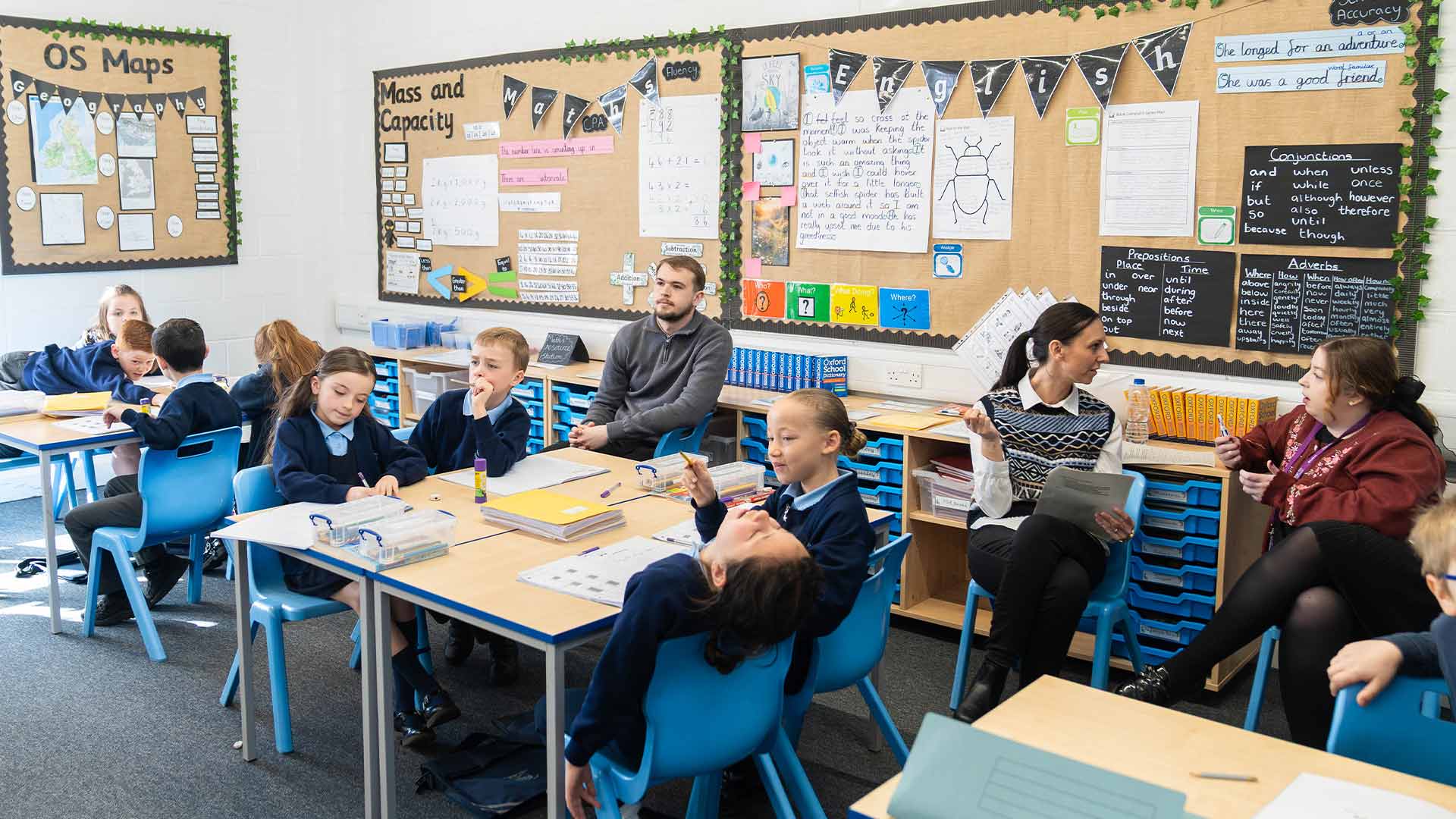 3 student teachers training in a primary school classroom with children sat at their desks